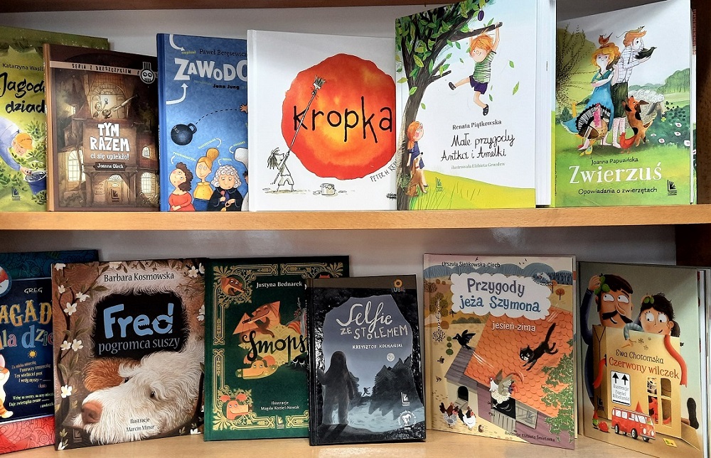 Książki dla dzieci wyeksponowane na półkach.